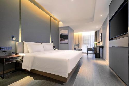 a bedroom with a large white bed and a television at Atour Hotel Wuhan Guanshan Avenue Guanggu Software Park in Wuhan