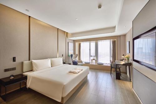 um quarto com uma grande cama branca e uma secretária em Atour Hotel Taixing Municipal Government Drum Tower Xintiandi em Taizhou