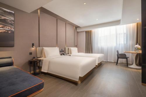 南通市にあるAtour Hotel Nantong Jinshaのベッド2台とテーブルが備わるホテルルームです。