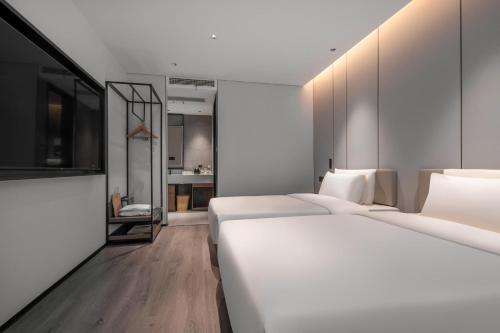 a room with three beds and a bathroom at Atour Hotel Jiaojiang Taizhou in Taizhou