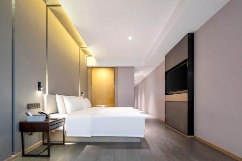 a bedroom with a white bed and a television at Atour Hotel Wuhan Guanshan Avenue Guanggu Software Park in Wuhan