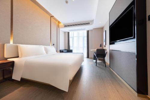 a hotel room with a large white bed and a desk at Atour Hotel Yibin West Railway Station in Yibin