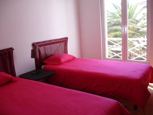 エシュポゼンデにあるHI Ofir – Pousada de Juventudeのピンクのシーツと窓が備わるドミトリールームのベッド2台分です。
