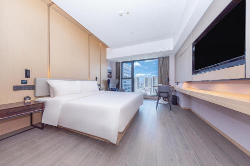 um quarto de hotel com uma cama branca e uma grande janela em Atour Hotel Xiaolan Zhongshan em Zhongshan