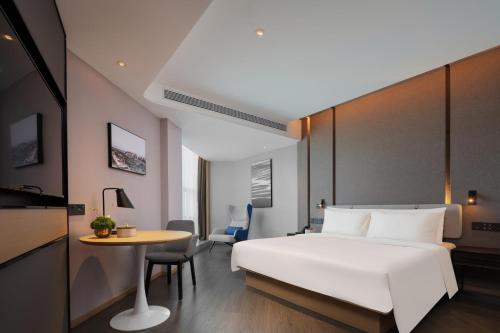 Un dormitorio con una gran cama blanca y una mesa en Atour Hotel Zezhou Road Jincheng, en Jingcheng