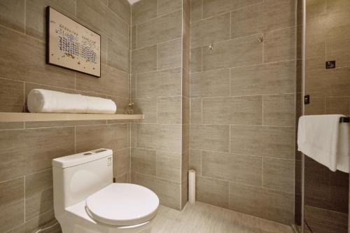 a bathroom with a toilet and a tile wall at Atour Hotel Taixing Municipal Government Drum Tower Xintiandi in Taizhou