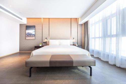 a bedroom with a bed and a large window at Atour Hotel Bohai International Plaza Binzhou in Binzhou