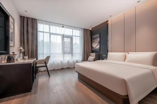 una camera d'albergo con un grande letto e una scrivania di Atour Hotel Jiaojiang Taizhou a Taizhou