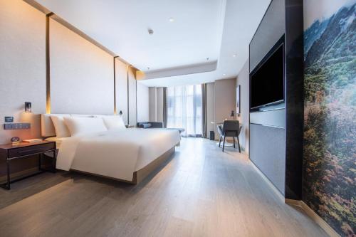 a hotel room with a large bed and a television at Atour Hotel Yibin West Railway Station in Yibin