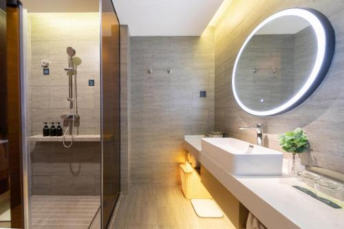 a bathroom with a sink and a shower with a mirror at Atour Hotel Yibin West Railway Station in Yibin