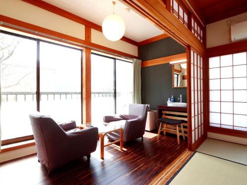 a living room with chairs and a table and windows at 富山県 よしのや旅館 in Nanto