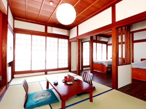 a room with a table and chairs and a bedroom at Yoshinoya Ryokan in Nanto