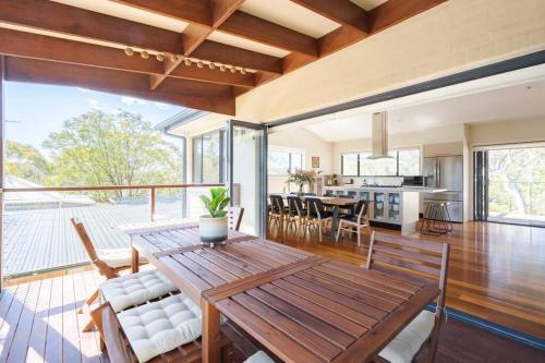 a dining room and kitchen with a wooden table and chairs at Alleura House Serene Bushland 4BR Families Groups in Leura