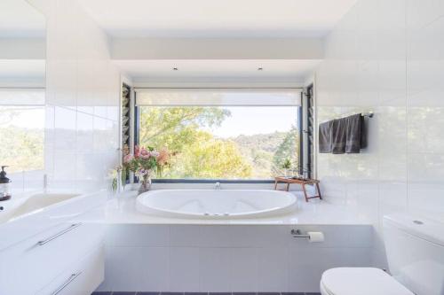 a white bathroom with a tub and a window at Alleura House Serene Bushland 4BR Families Groups in Leura
