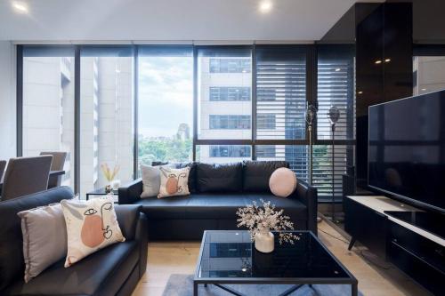 a living room with a couch and a tv at Castlereagh - 2BR Sydney CBD Views Hyde Park Families & Groups in Sydney