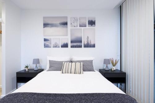 a bedroom with a large white bed with two tables at Castlereagh - 2BR Sydney CBD Views Hyde Park Families & Groups in Sydney