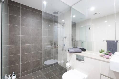 a bathroom with a shower and a toilet and a sink at Castlereagh - 2BR Sydney CBD Views Hyde Park Families & Groups in Sydney