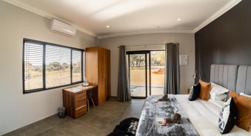 a bedroom with a bed and a window and a desk at Leeuwkop Hunting Safaris in Kimberley