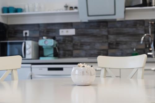 a white vase sitting on a table in a kitchen at MYKONOS APARTMAN in Makó