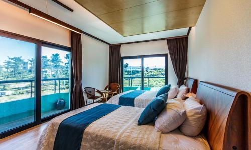 a bedroom with two beds and a large window at Cutie Pie Hotel in Jeju