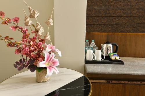 a vase with pink flowers sitting on a table at Brio Hotel in Kolkata