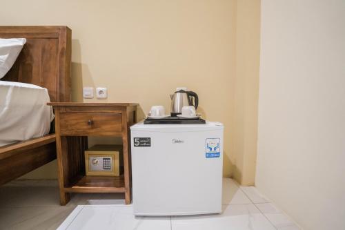 a small refrigerator in a room next to a bed at Andi Beach House in Canggu