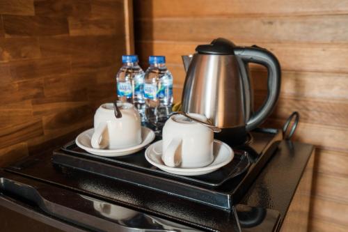 a tea kettle and cups on a stove with bottles of water at Andi Beach House in Canggu
