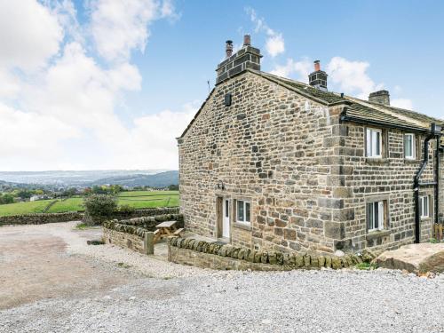 an old stone house with a dog in front of it at Spinners Cottage in Keighley
