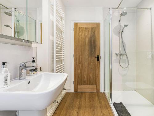 een witte badkamer met een wastafel en een douche bij Spinners Cottage in Keighley