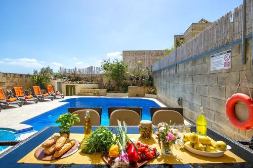 una mesa con comida junto a una piscina en Kampnar Holiday Home, en Kerċem