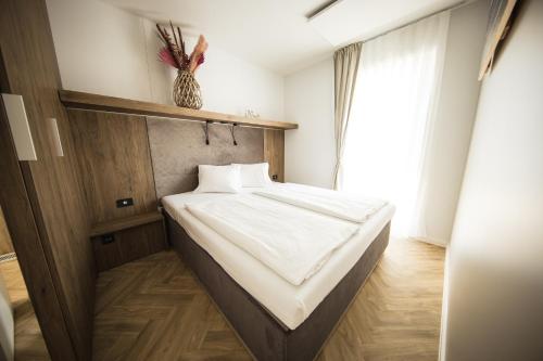 a bedroom with a bed with white sheets and a window at Sonnenthermen Chalets & Therme included - auch am An- & Abreisetag! in Lutzmannsburg