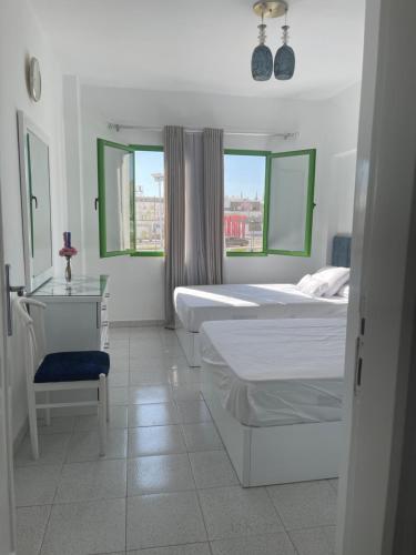 沙姆沙伊赫的住宿－City Center Apartment - Neama Bay，一间卧室设有两张床、一张桌子和一个窗口。