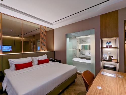 a bedroom with a large bed and a bathroom at Grand Zuri Lubuklinggau in Lubuklinggau