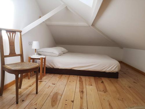 een slaapkamer met een bed en een stoel op zolder bij Maisonnette de Charme à 10min de Fontainebleau in Héricy