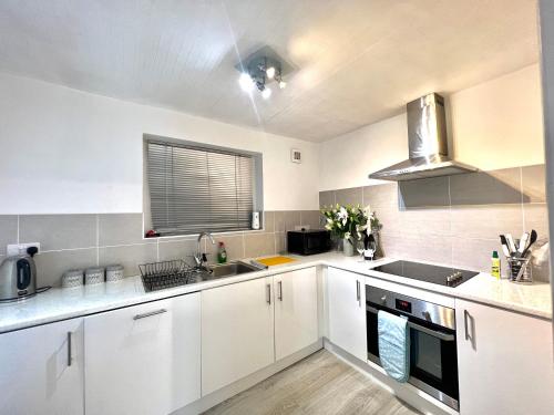 a kitchen with white cabinets and a sink and a window at Beach Front Apartment with Free Parking, St Annes in Lytham St Annes