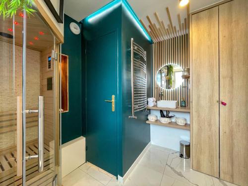 La salle de bains est pourvue d'une porte bleue et d'un miroir. dans l'établissement Votre Escale Boule d Or Sauna & Spa, à Niort