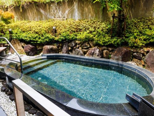 una piscina en un jardín con cascada en KAMENOI HOTEL Yamato Heguri, en Heguri