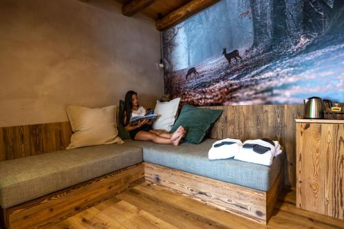 a woman sitting on a couch reading a book at Teverone Suites & Wellness in Lamosano