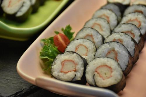 a plate of sushi and salad on a table at Al Meroz Hotel Bangkok - The Leading Halal Hotel in Bangkok