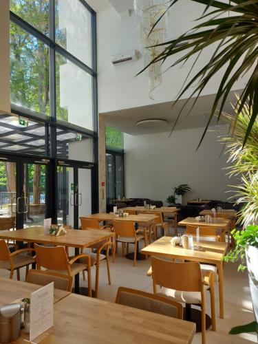 a restaurant with wooden tables and chairs and windows at Gartenhotel Altmannsdorf in Vienna