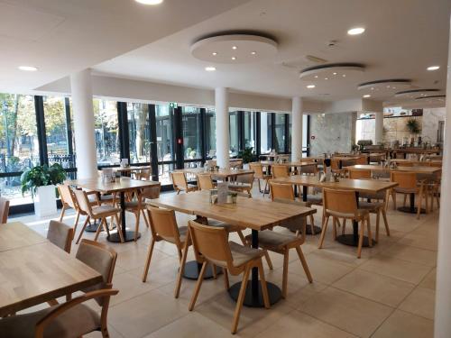 a restaurant with wooden tables and chairs and windows at Gartenhotel Altmannsdorf in Vienna
