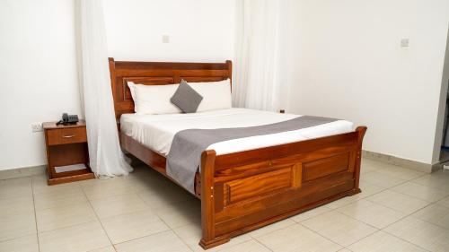 una camera con letto in legno e lenzuola bianche di Whirlspring Hotel a Kisumu
