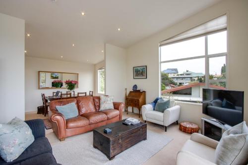 a living room filled with furniture and a large window at Havelock Wine Down - Havelock North Holiday Home in Havelock North