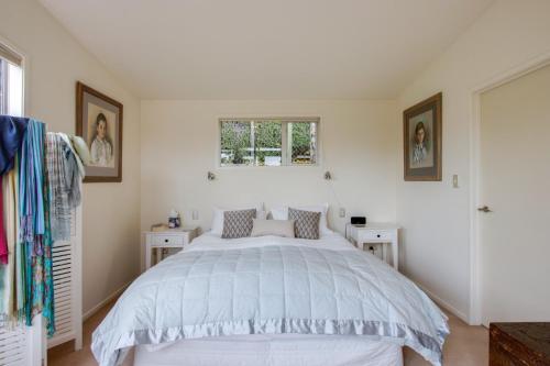a bedroom with a large bed and two white tables at Havelock Wine Down - Havelock North Holiday Home in Havelock North