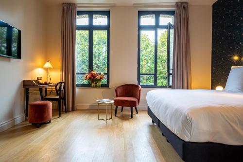 um quarto de hotel com uma cama, uma secretária e janelas em L'Invitation au Voyage Hôtel- Espace Bien-être - Bar Lounge em Honfleur