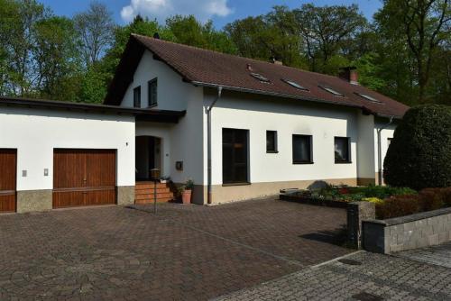 ein weißes Haus mit einer Garage und einer Auffahrt in der Unterkunft Ferienwohnung Wilfried Schlor in Merzig