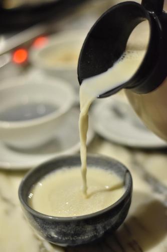 a person is pouring milk into a bowl at Al Meroz Hotel Bangkok - The Leading Halal Hotel in Bangkok