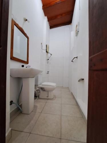 a bathroom with a toilet and a sink and a mirror at Etnico Surf Resort in Arugam Bay