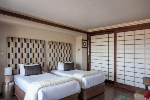 two beds in a room with white walls and mats at Inverdoorn Game Reserve Lodge in Breede River DC