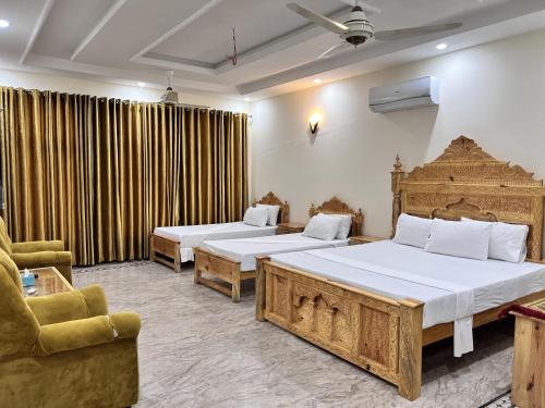 um quarto de hotel com duas camas e uma cadeira em Royal Blue Inn House em Islamabad